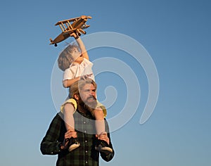 Father and son. Boy with toy aeroplane sitting on fathers shoulders. Happy father child moment. Father piggybacking his