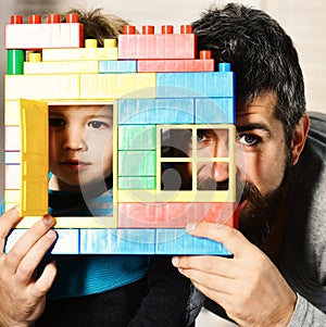 Father and son with calm faces behind colorful bricks construction
