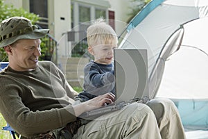 Father and son camping with laptop