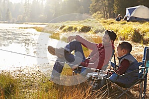 Father and son on a camping trip fishing by a lake photo