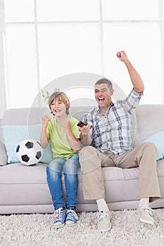 Father and son celebrating success while watching soccer match