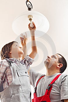 Father and son changing lightbulb in a ceiling lamp