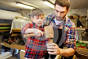 Father and son with chisel working at workshop