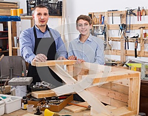 Father and son chiselling a wooden bench in workshop