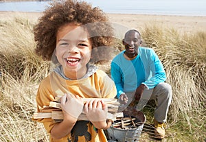 Father And Son Collecting Firewood On Beach