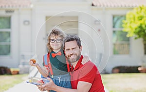 Father and son come back from school. Little schoolboy eating tasty lunch outdoors.