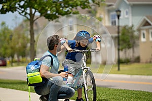 Father and son concept. Father teaching son in protective helmet riding bike. Father helping son to ride a bicycle