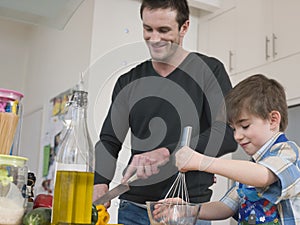 Father And Son Cooking Food In Kitchen