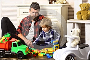 Father and son create toys from bricks. Dad and kid build of plastic blocks. Father and son playing toys wooden blocks