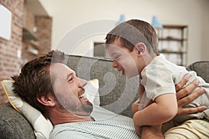 Father And Son Cuddling On Sofa Together