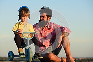 Father and son. Dad help his child ride a bicycle. Lovely father teaching son riding bike