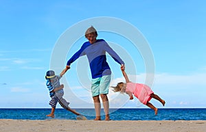 Father with son and daughter play at beach