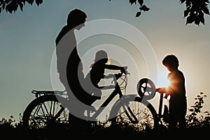 Father with son and daughter riding bikes at sunset