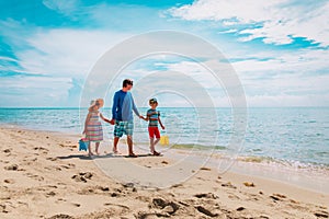 father with son and daughter walking on beach, family summer vacation