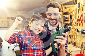 Father and son with drill working at workshop