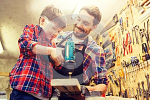 Father and son with drill working at workshop