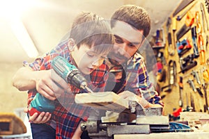 Father and son with drill working at workshop