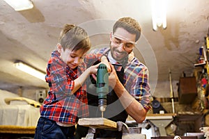 Father and son with drill working at workshop