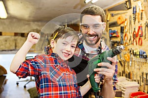 Father and son with drill working at workshop