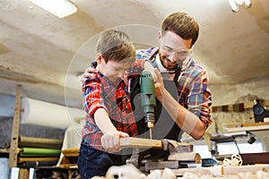 Father and son with drill working at workshop