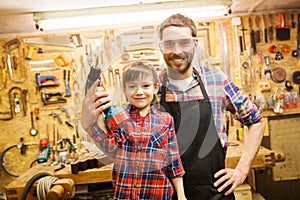 Father and son with drill working at workshop