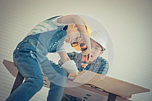 Father and son drilling wood on workshop table for home improvement, for family bonding father and son love concept