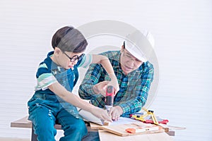 Father son is drilling wood on workshop table for home improvement, for family bonding father and son love concept