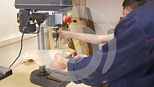 Father and son drills the wooden plank using joinery machine in carpentry workshop