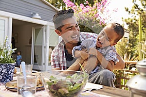 Father And Son Eating Outdoor Meal In Garden Together