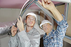 Father and son electricians working on buildings ceiling