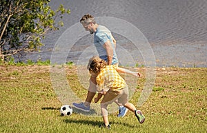 Father and son enjoy a friendly game of football. happy childhood of son playing with father. father and son summer