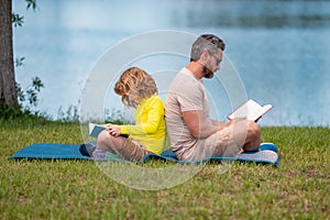 Father and son enjoy spending quality time reading books outdoors. Dad and kid son enjoy nature while reading book