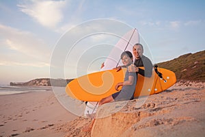 Father and son enjoying beach day with a surfboard at sunset