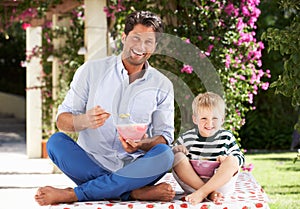 Father And Son Enjoying Breakfast Cereal Outdoors