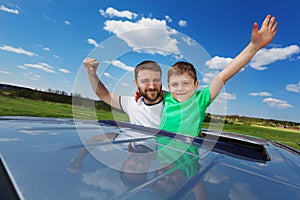 Father and son enjoying freedom on sunroof of car