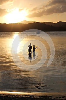 Father and son family fishing at sunset