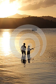 Father and son family fishing at sunset