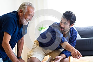 Father and son family time together at home concept. Bearded olf Father and Bearded middle age Son Playing Toy train on floor at