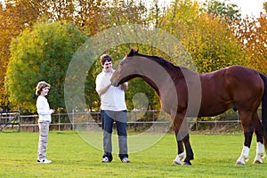 Father and son feeding horse on sunny day