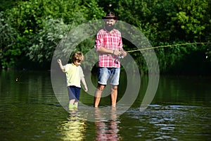 Father and son fishing. Fly fishing for trout. Happy father and son fishing in river holding fishing rods. Concept of a