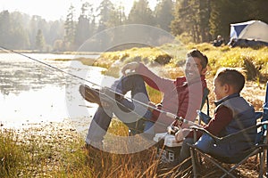 Father and son fishing by a lake, dad looks to camera