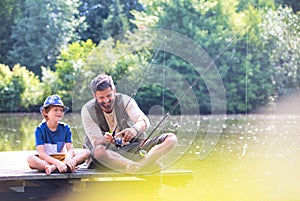 Father and son fishing in Lake while sitting on pier