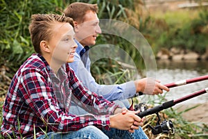 Father and son fishing on river