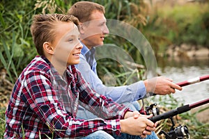 Father and son fishing together on lake