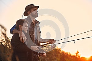 The first joint fishing of adult father and teen son in warm, sunny day.