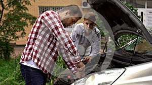 Father and son fixing car, dad teaching teen boy to repair engine, role model