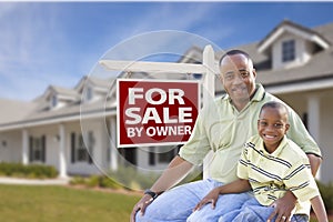 Father and Son In Front of For Sale By Owner Sign and House