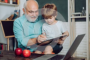 Father and son - generation people concept. Kid with old teacher learning in class on background of blackboard. Little