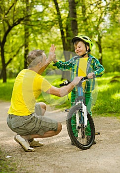 Father and son give high five while cycling in the park