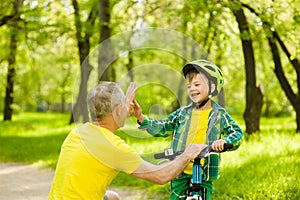 Father and son give high five while cycling in the park